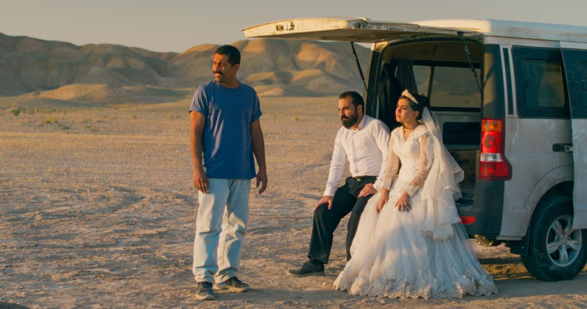 Three people are unsure of what to do in the desert.