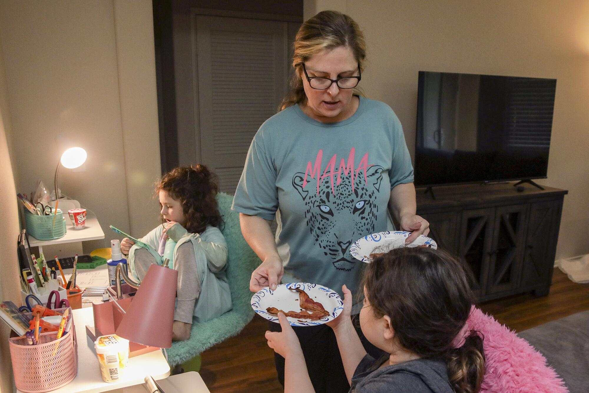 Alison Goldberg, 43, gives lunch to Savannah Singer, foreground, and Madelynn Singer while attending online school.