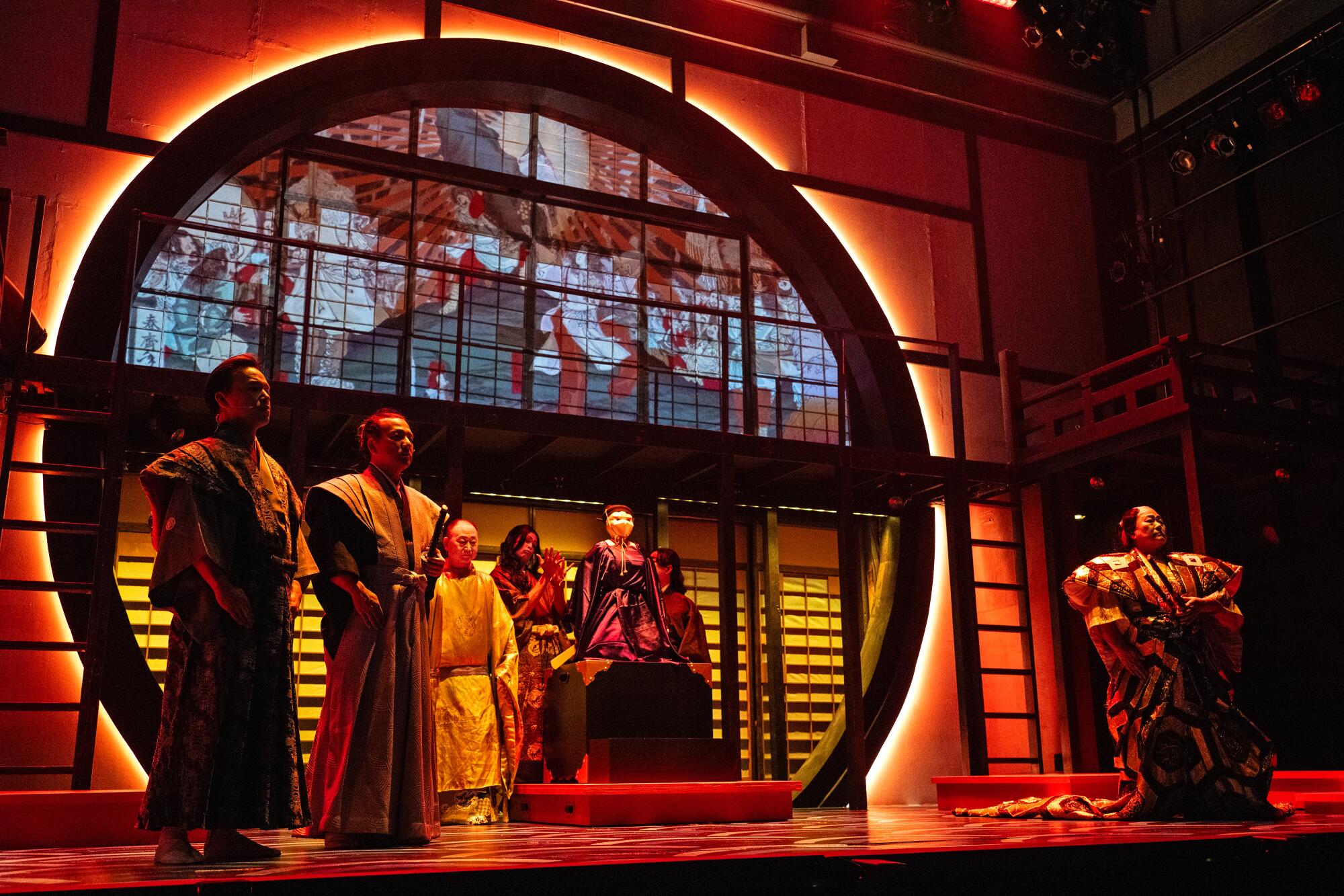 Several people in traditional Japanese robes on a stage emitting an orange glow.