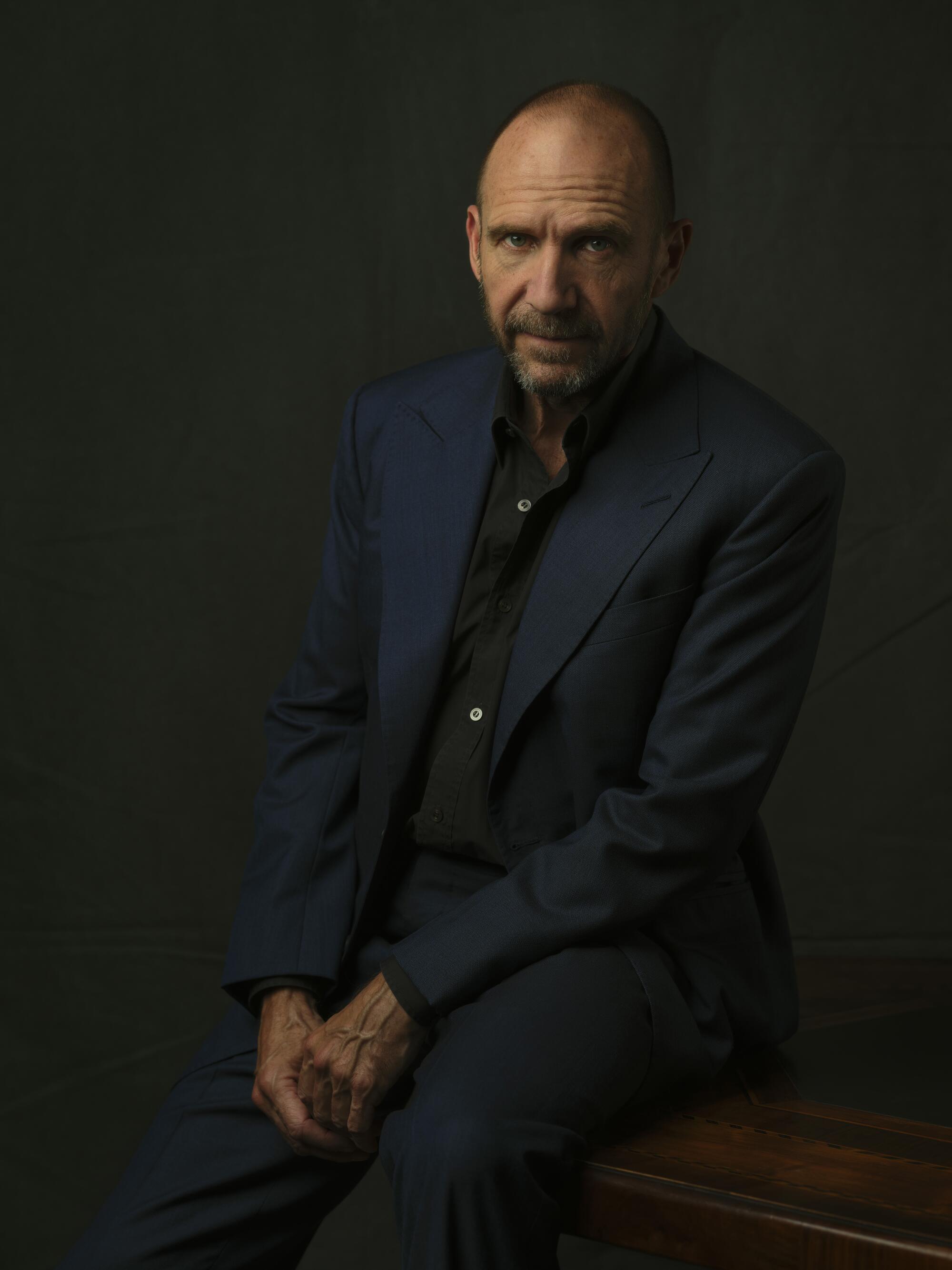 Actor Ralph Fiennes sits, looking serious