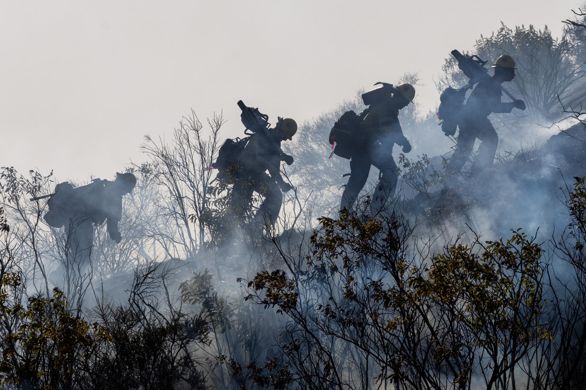 Camp crewmembers hike up a steep hillside as they battle the Frankiln fire in Malibu. More photos