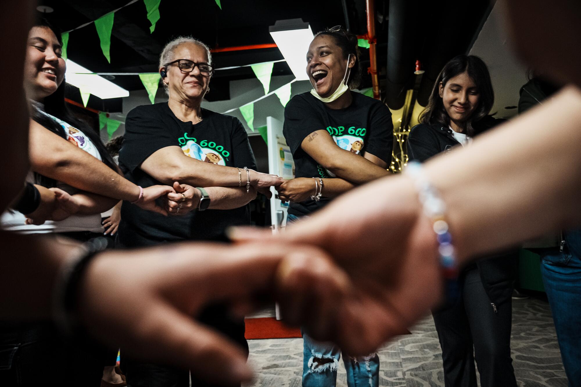 Women and girls cross their arms and hold hands in a circle.