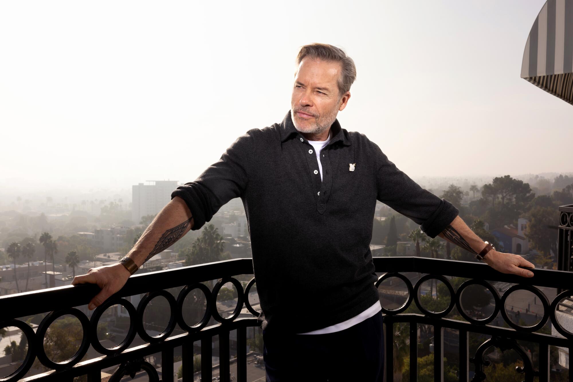A man is photographed on a balcony overlooking Los Angeles.