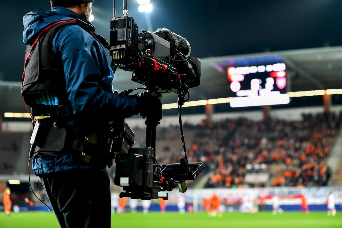 Cameraman behind playing field during soccer match.