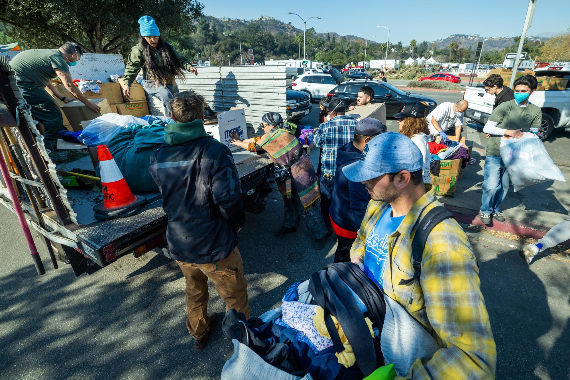 Volunteers help people load bags of goods.