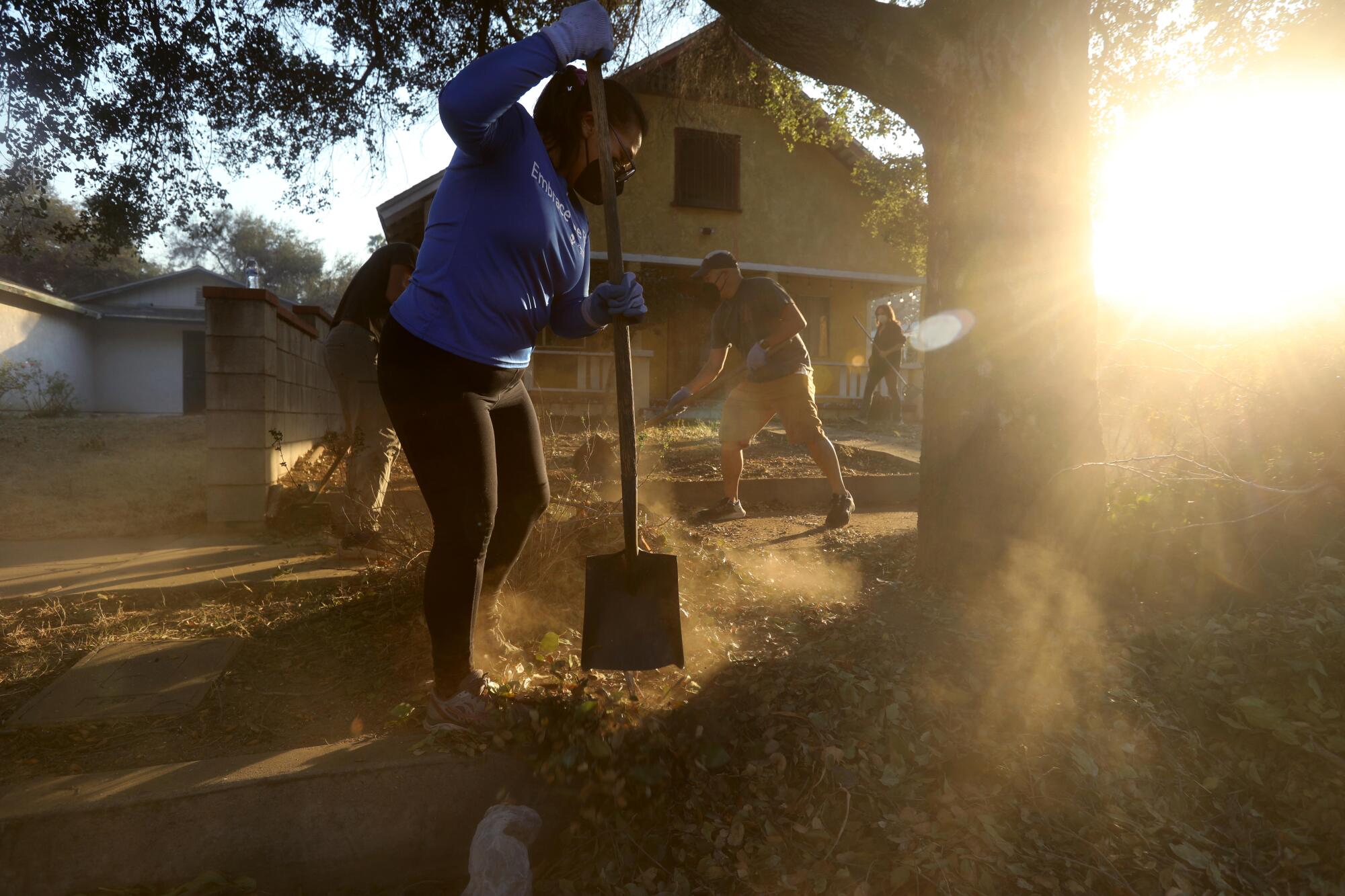 A woman clears debris in front of a home.