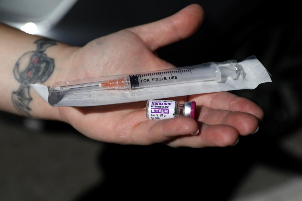 A person holding the overdose reversal drug naloxone and a syringe