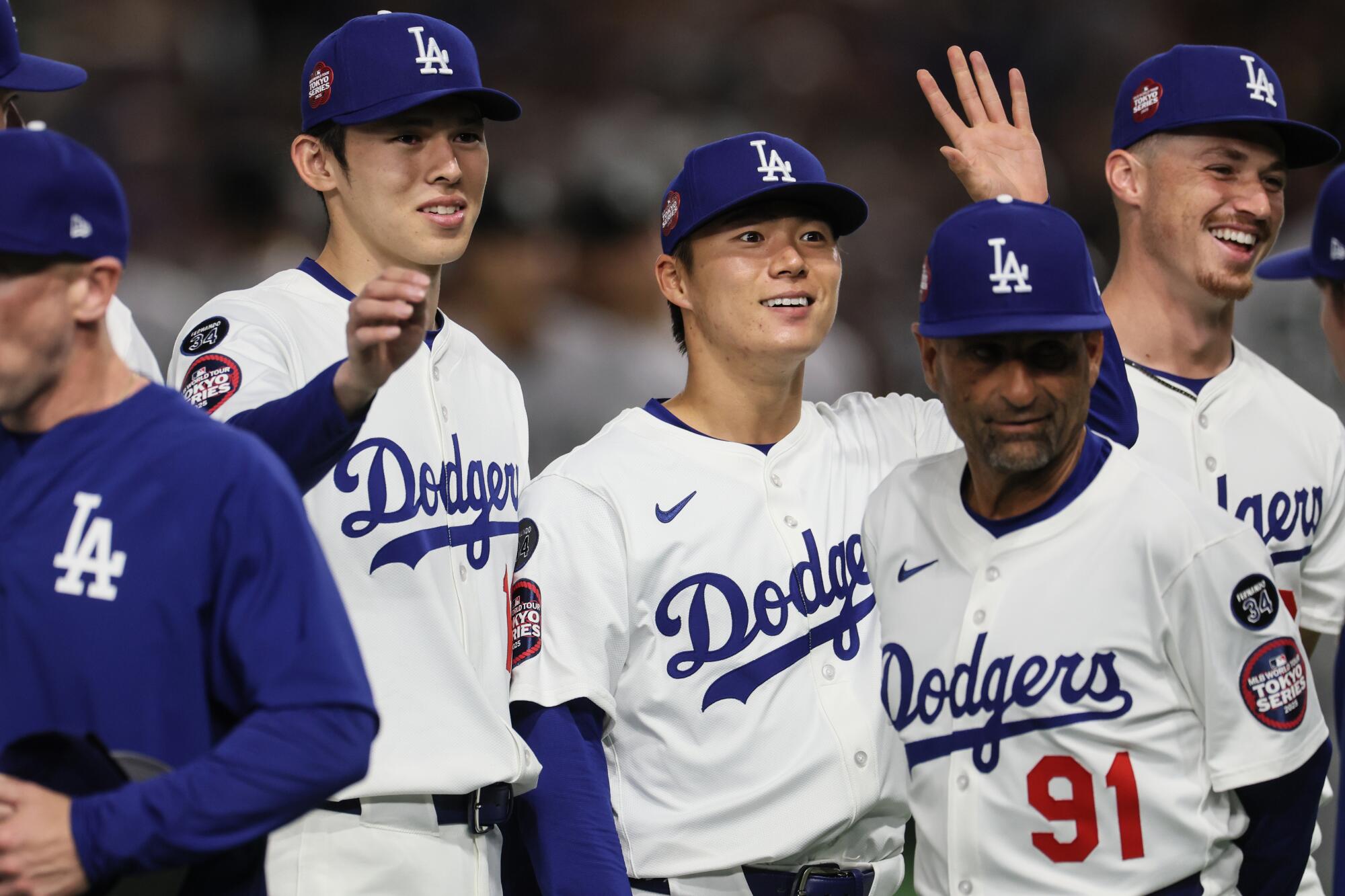 Dodgers pitchers Roki Sasaki and Yoshinobu Yamamoto wave to fans as they are introduced before an exhibition game Saturday.