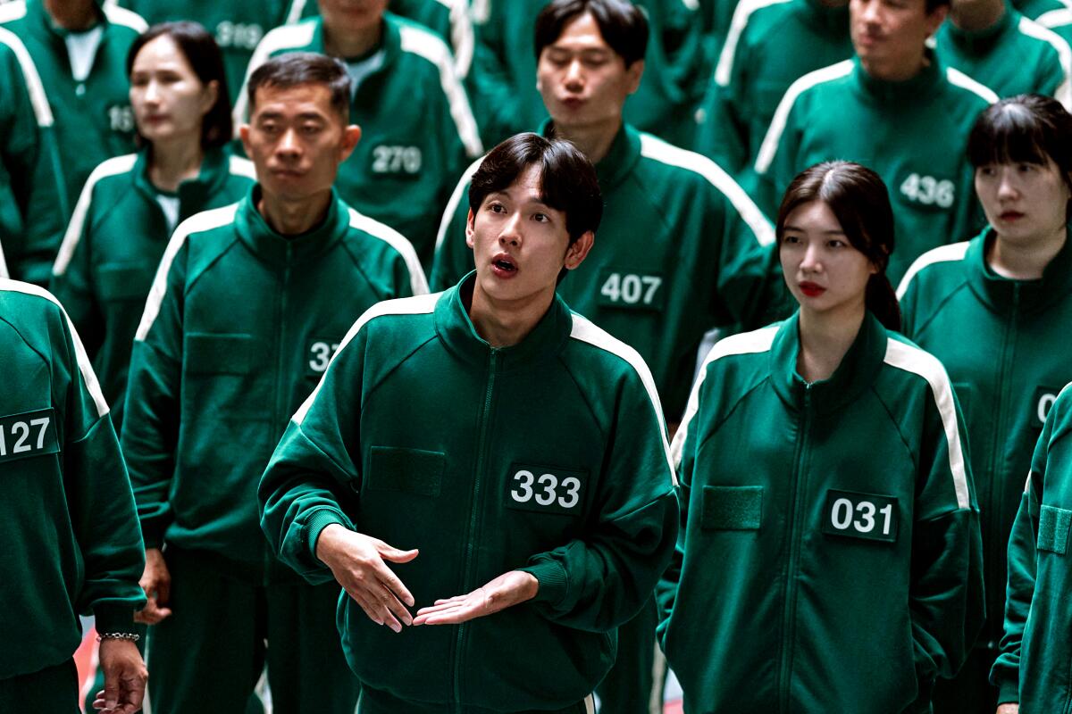 A group of people in green tops with white stripes and white numbers.