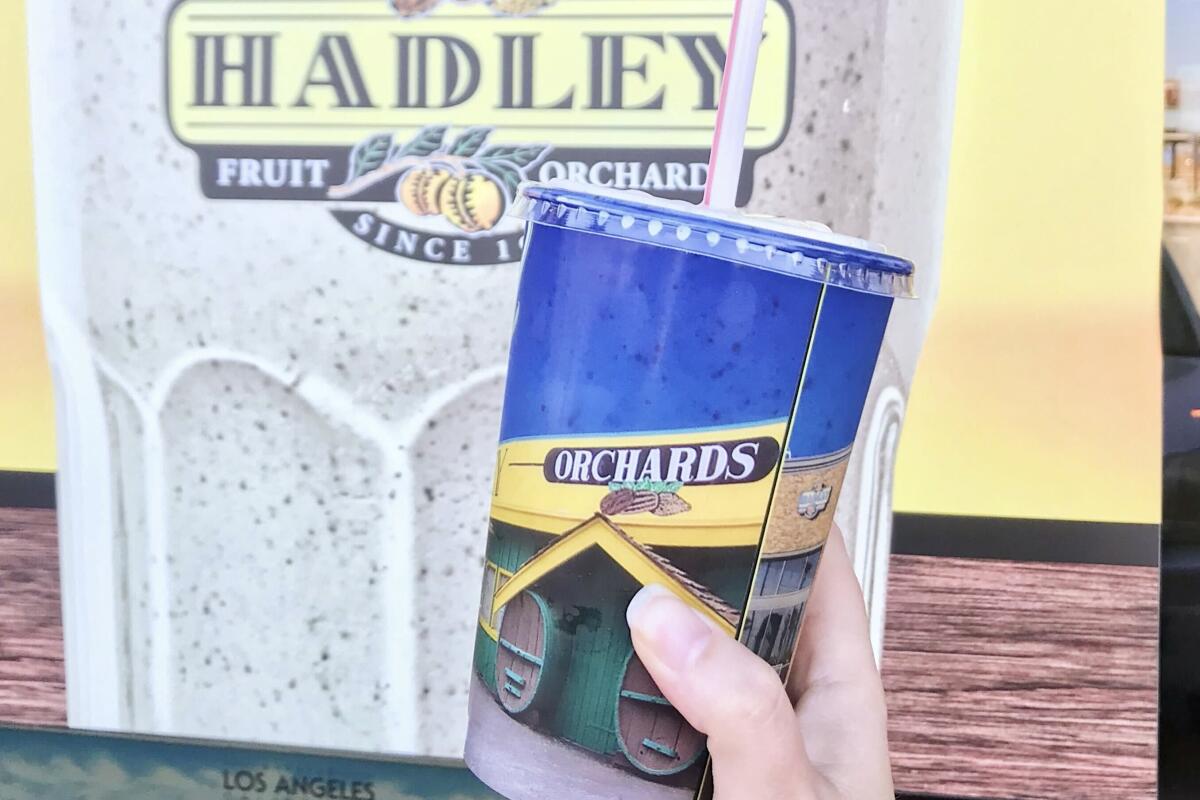 A hand holds up a date shake from Hadley Fruit Orchards in Cabazon.
