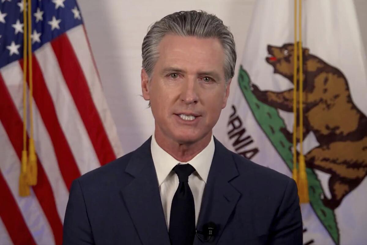 Gavin Newsom speaking before furled U.S. and California flags