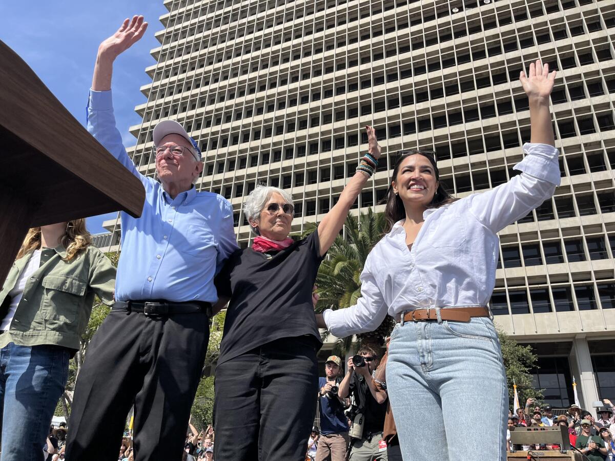 Sen. Bernie Sanders, singer Joan Baez & U.S. Rep. Alexandria Ocasio-Cortez wave to crowd during the Fighting Oligarchy rally