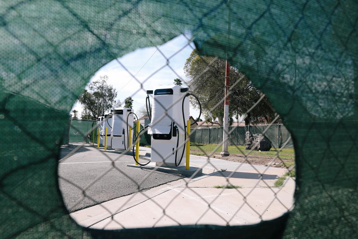Electric vehicle charging station seen through a chain-link fence