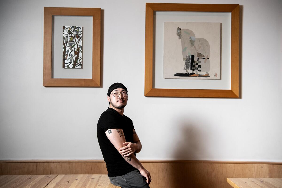 A portrait of Kim in a black shirt against the wall inside the dining room of Kinn.