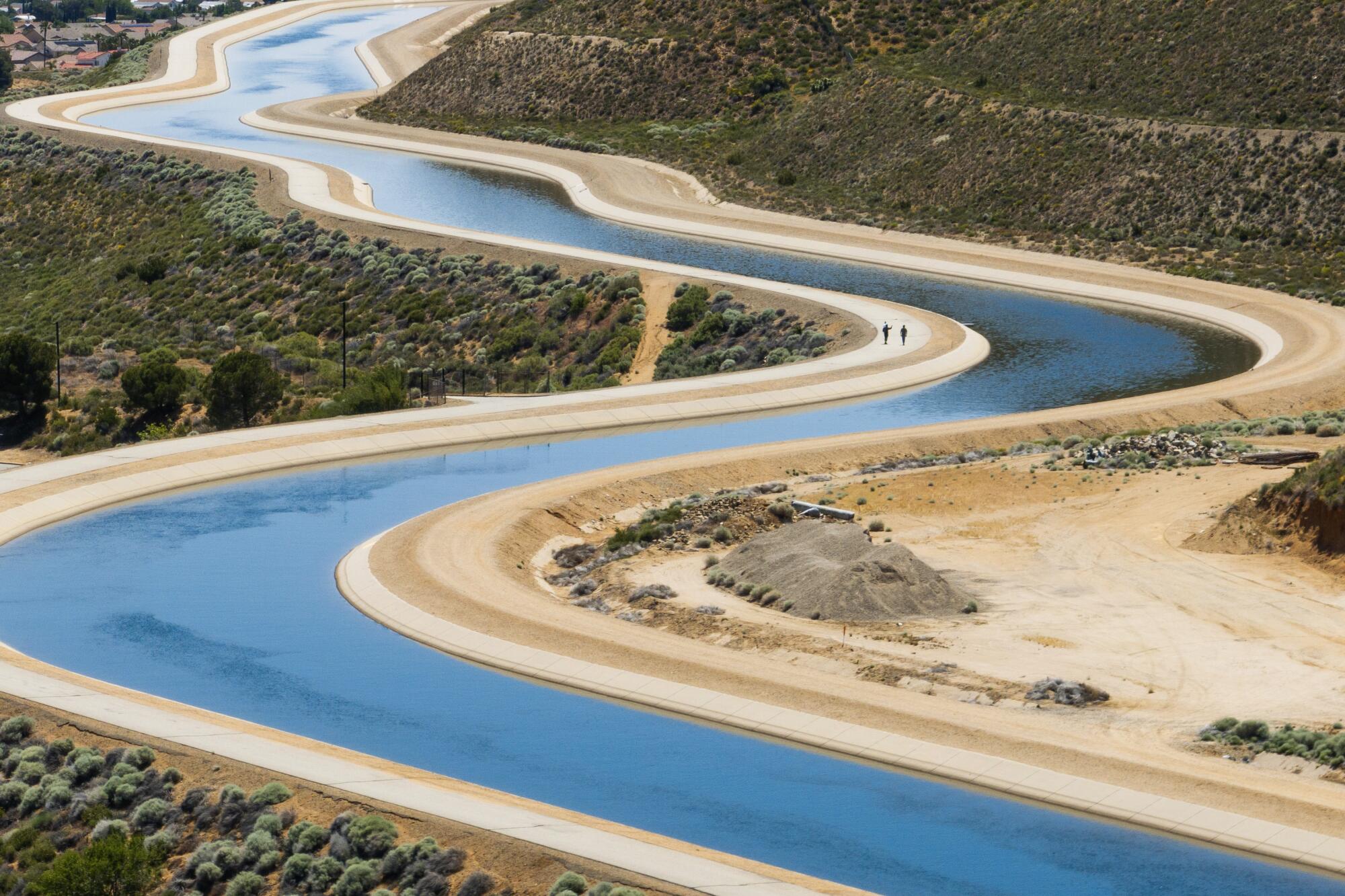 An aqueduct winds through a desert shrubland.