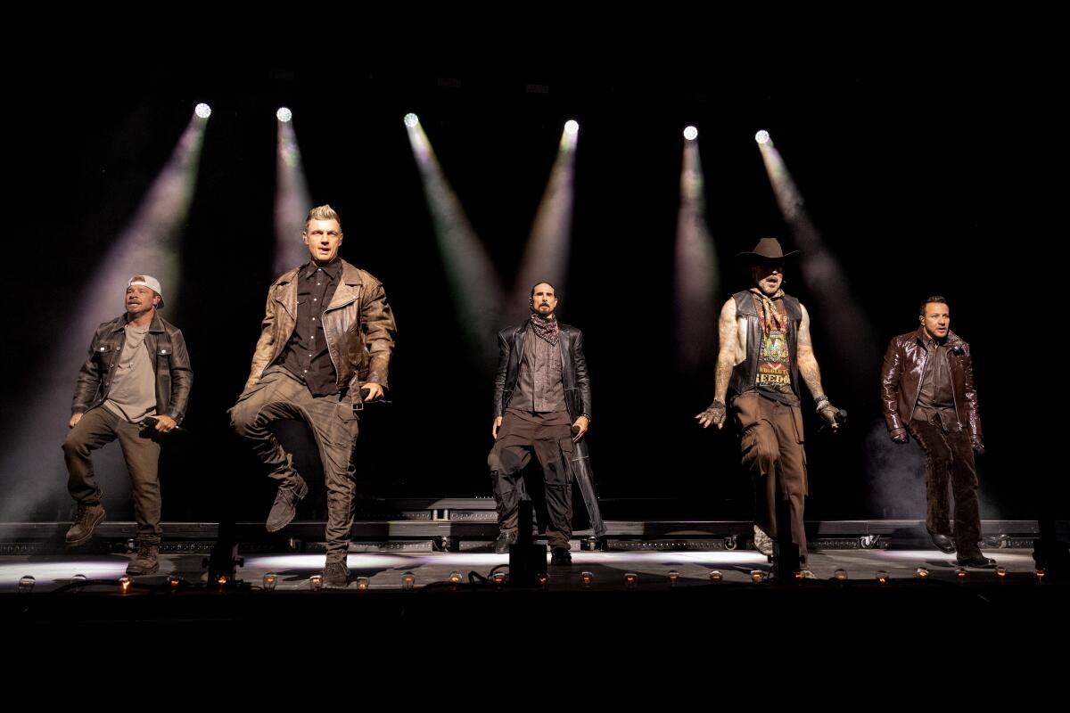 The Backstreet Boys, in leather vests and jackets, perform onstage.