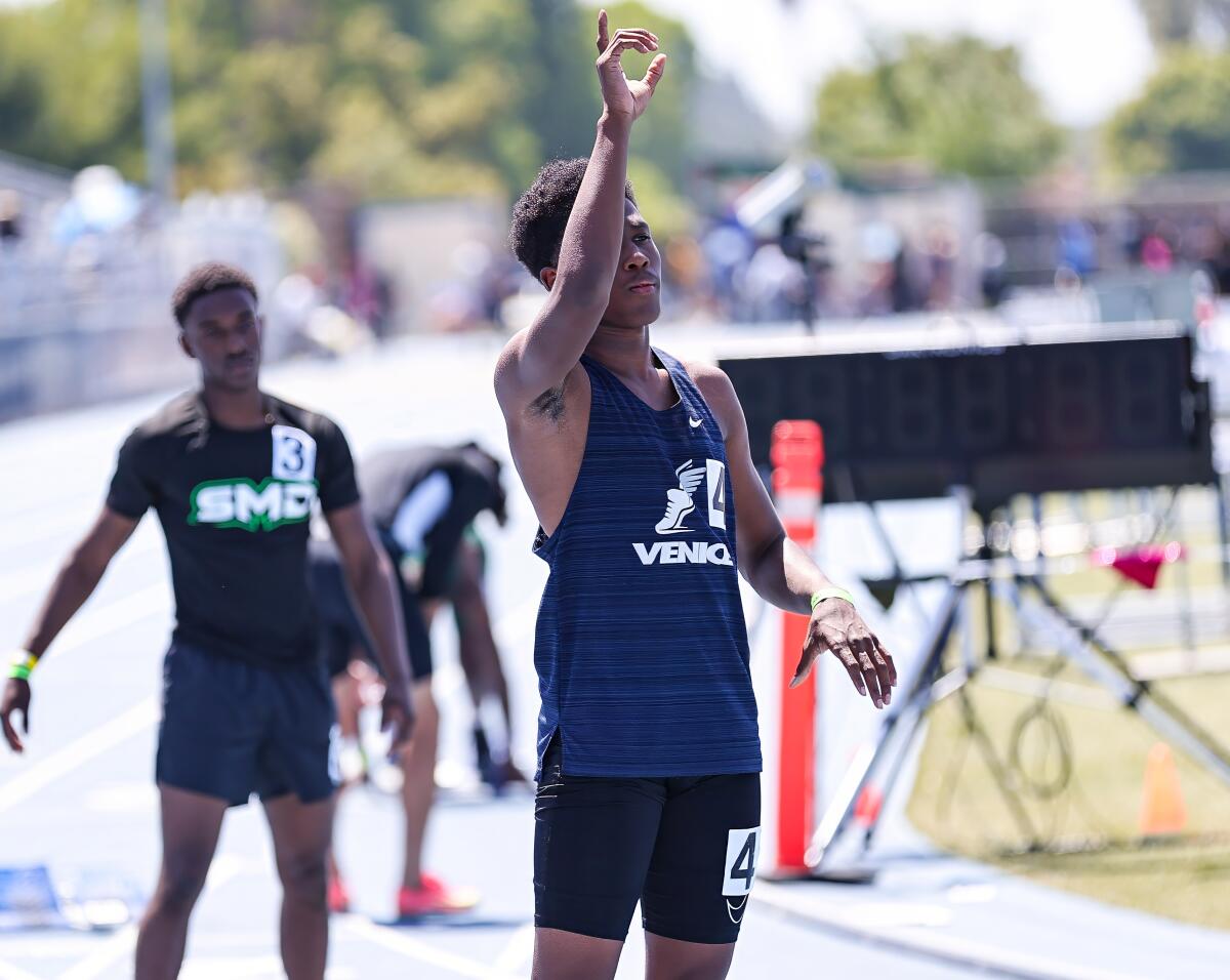 Nathan Santa Cruz holds up his right ram as he prepares to enter the starting blocks for a 400-meter race.