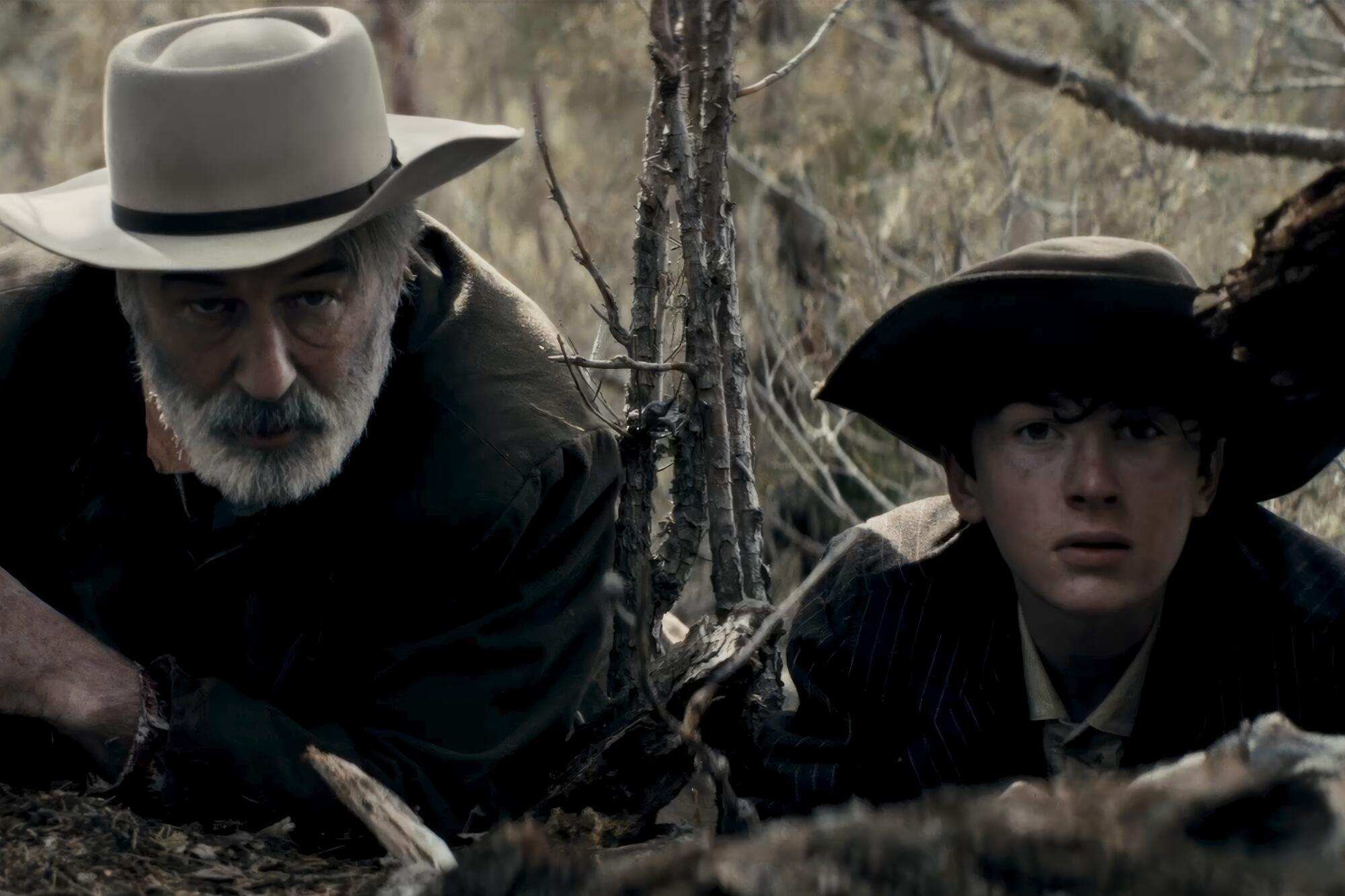 A grizzled man and a boy hide in the woods.