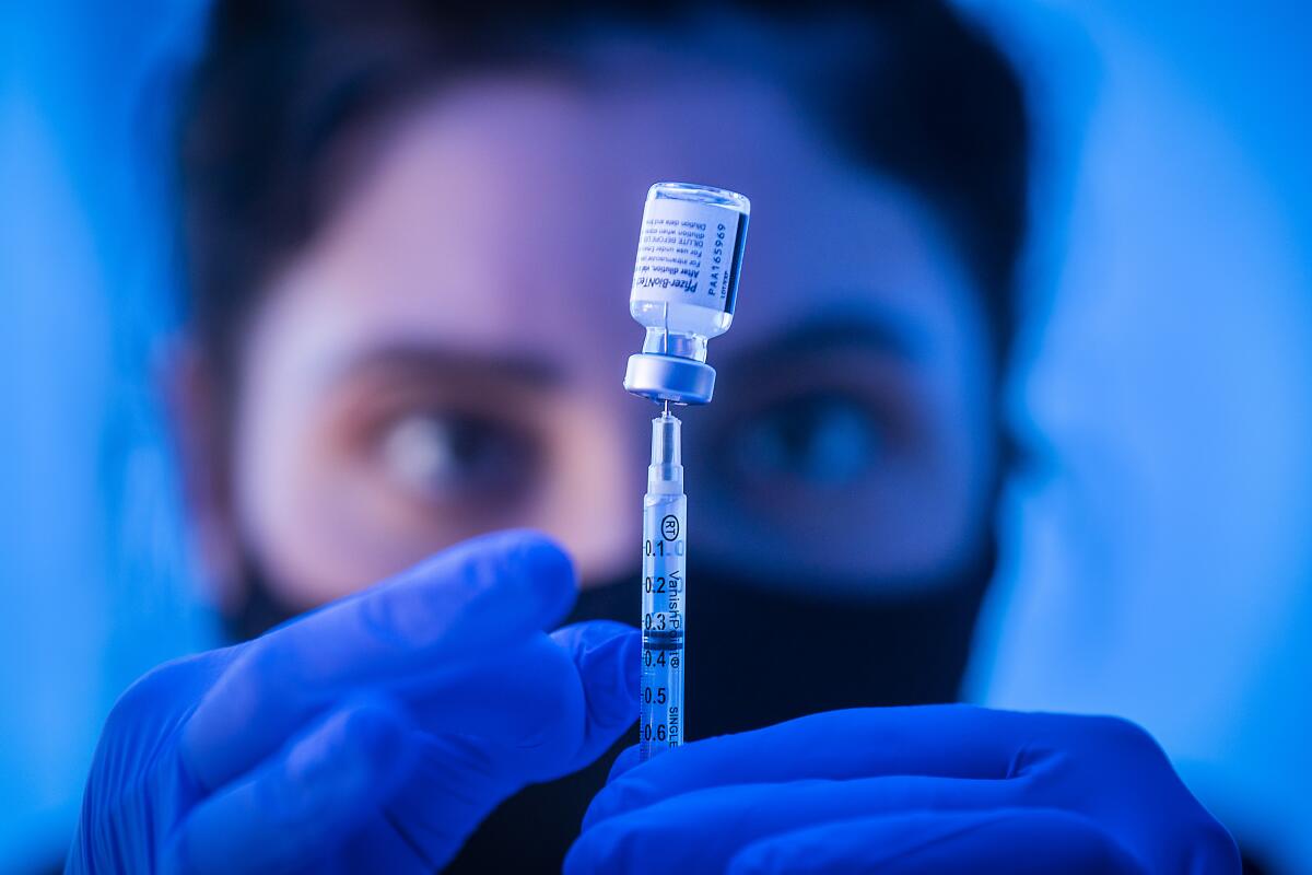 A medical student loads a COVID-19 vaccine.