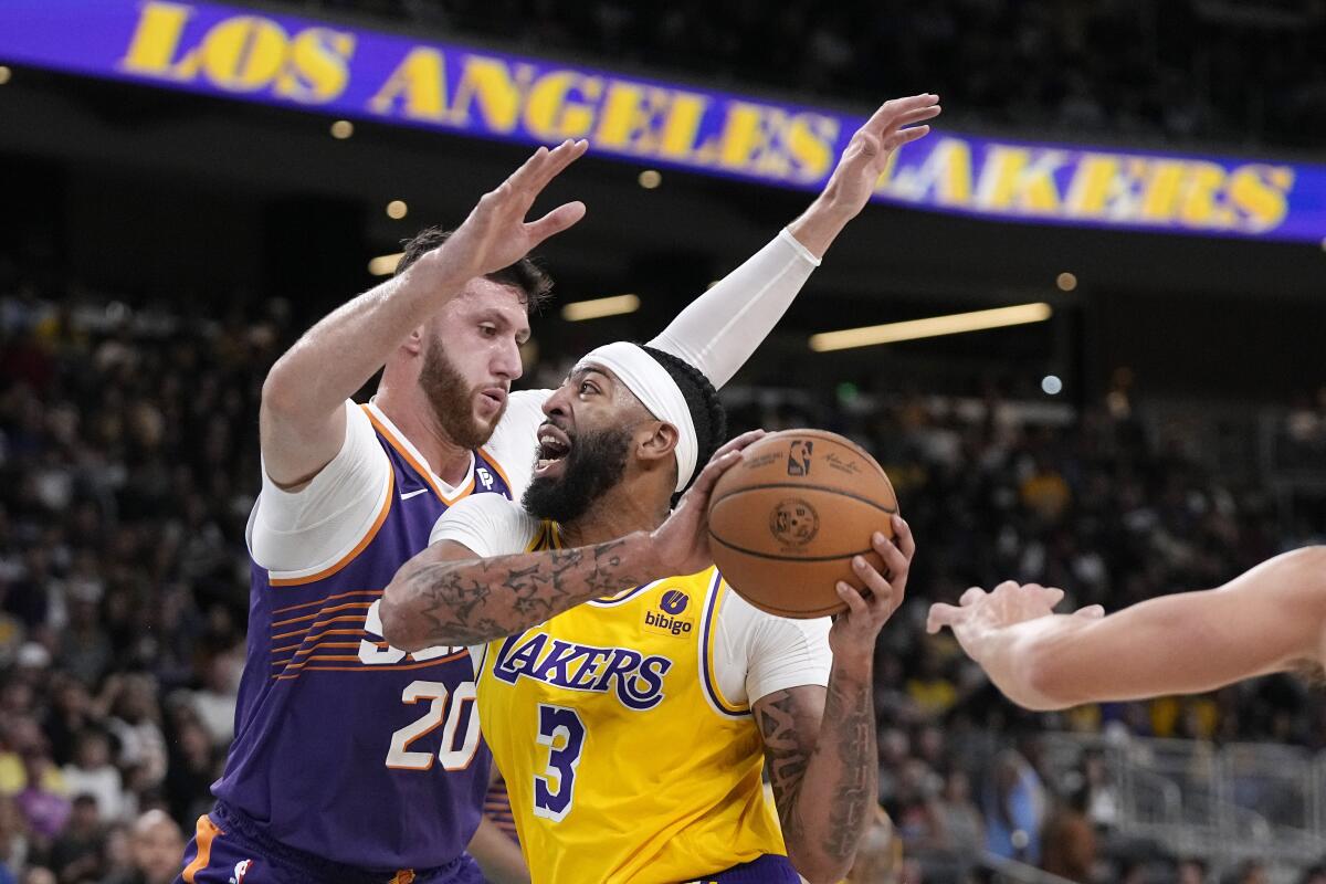 Lakers forward Anthony Davis, right, goes up for a shot while closely defended by Suns center Udoka Azubuike.