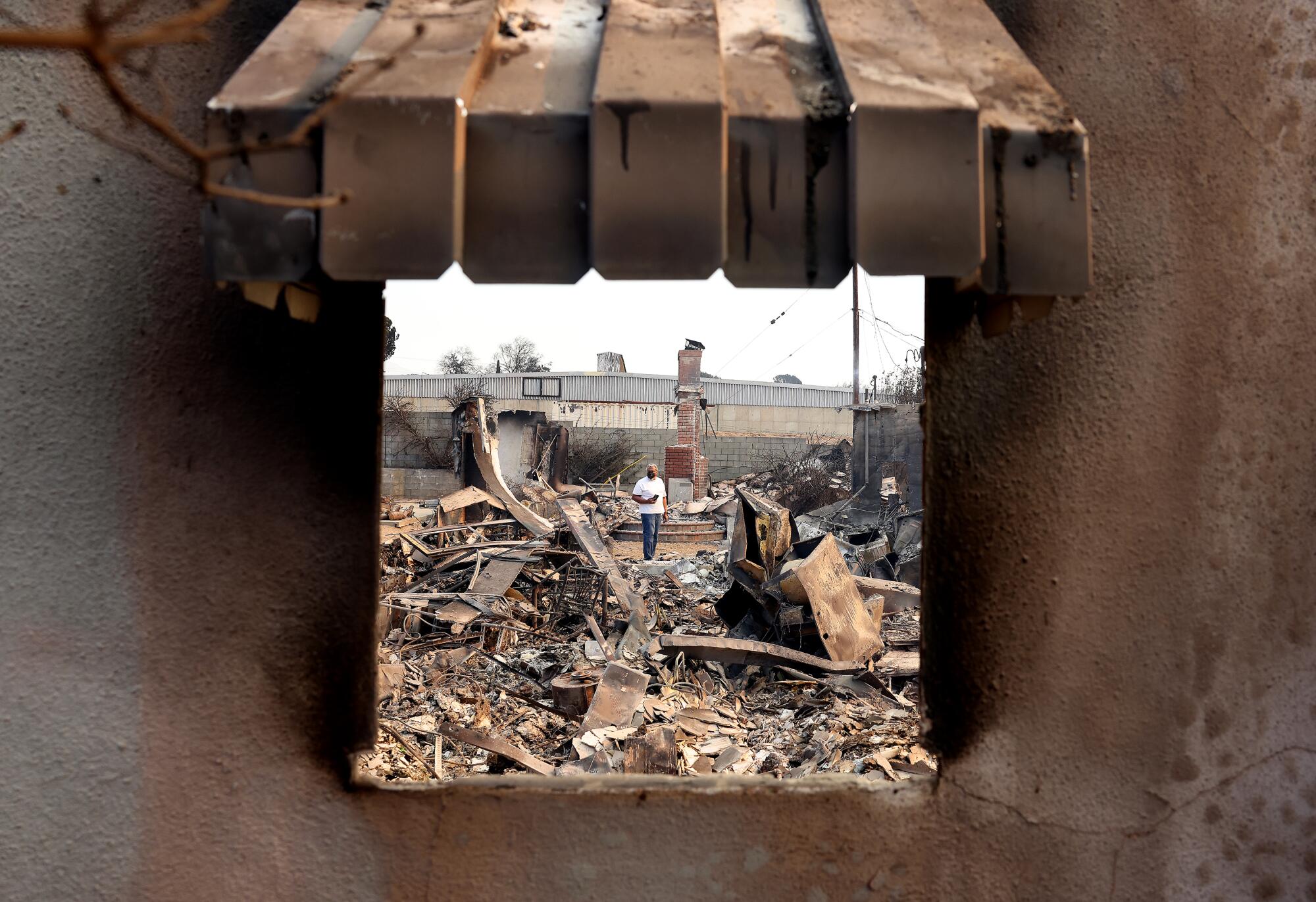 The small figure of a man is seen through a window frame of a gutted building,