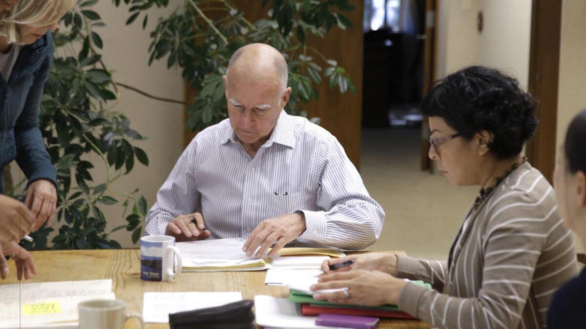 Gov. Jerry Brown, signs bills in his Capitol office on Oct. 9, 2015.